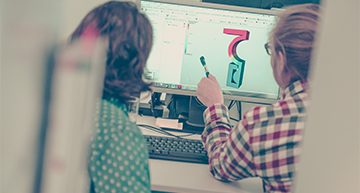 Two engineers looking at a computer screen showing a 3D CAD model